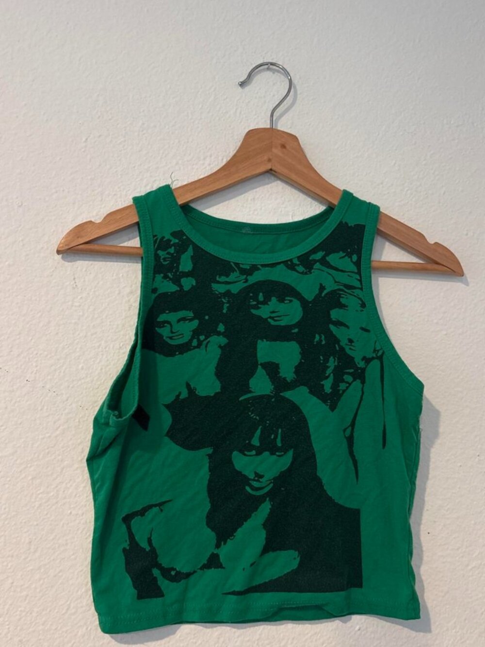 Green crop top with black graphic of multiple faces
